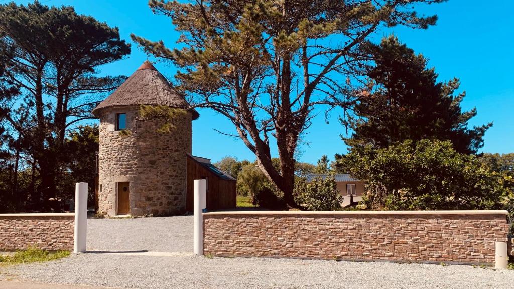 un bâtiment avec un mur en briques et une tour dans l'établissement MOULIN DE KERNOT, à Cléden-Cap-Sizun