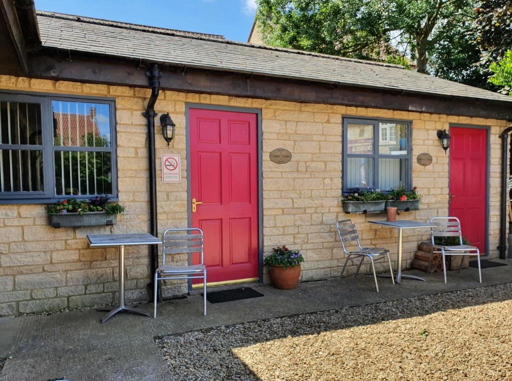 a house with red doors and two tables and chairs at Cross Swords Rooms, Skillington in Skillington