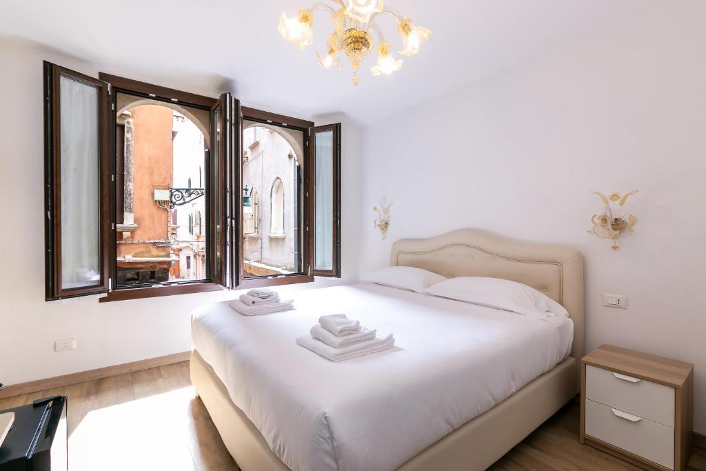 a bedroom with a white bed and a chandelier at Rialto Suite 707 in Venice
