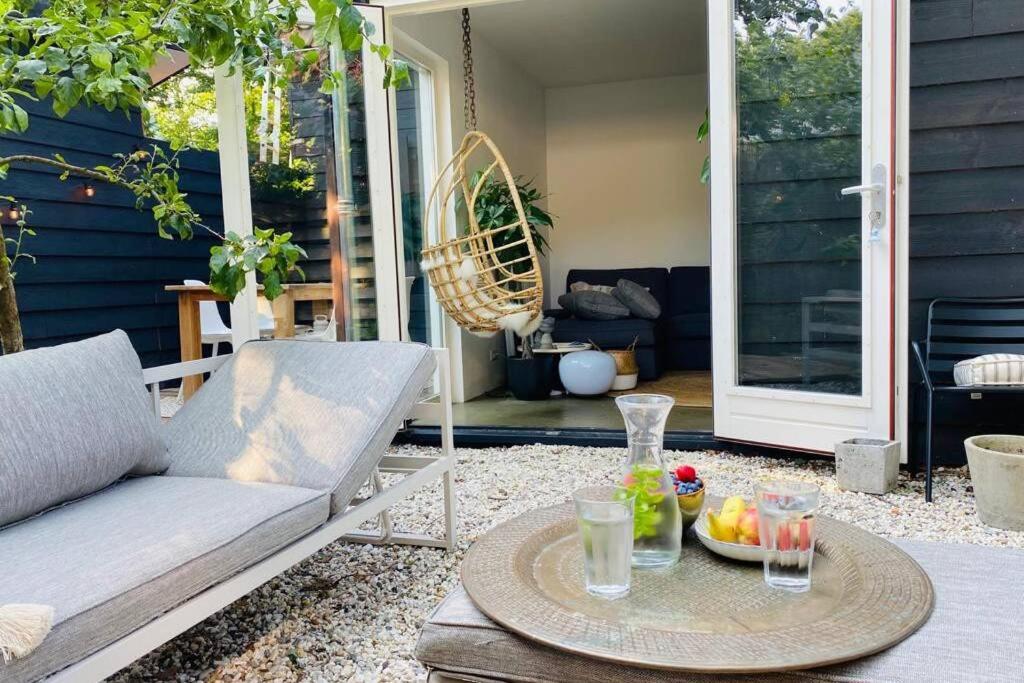 a patio with a couch and a table with drinks on it at Holiday home De Heer van Bergen in Bergen