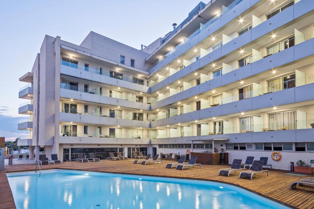 un hotel con piscina di fronte a un edificio di Hotel Balneario Playa de Comarruga a Comarruga