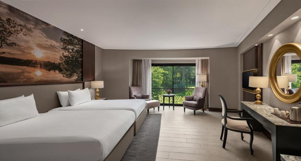 サパンジャにあるNG サパンジャ ウェルネス ＆ コンベンションのベッド2台とデスクが備わるホテルルームです。