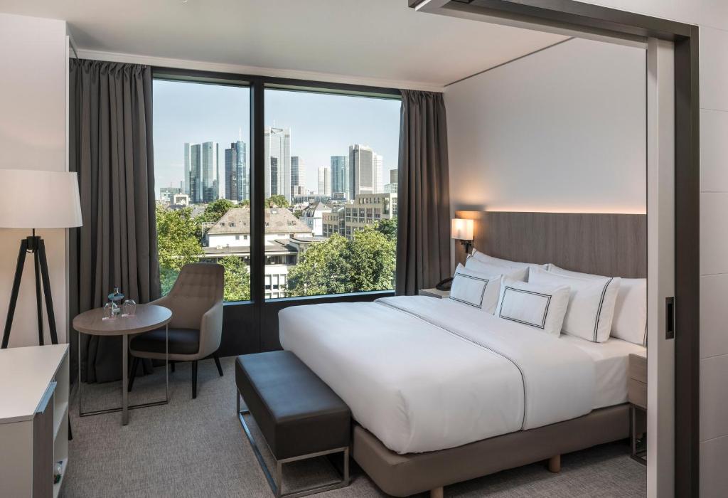 ein Hotelzimmer mit einem großen Bett und einem großen Fenster in der Unterkunft Meliá Frankfurt City in Frankfurt am Main