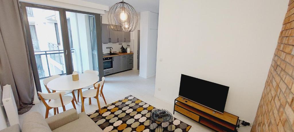 a living room with a tv and a table with chairs at Central Apartments Ogrody 3 & Parking in Gdańsk