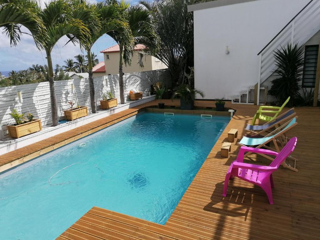 a swimming pool with two chairs and a table and a purplevisorvisor at Villa canne à sucre in Saint-Louis