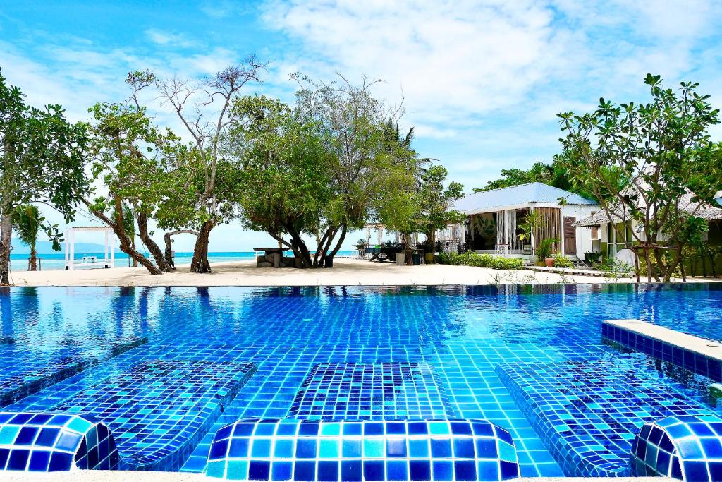 una piscina con azulejos azules frente a un complejo en Sabaii Bay Resort, en Baan Tai