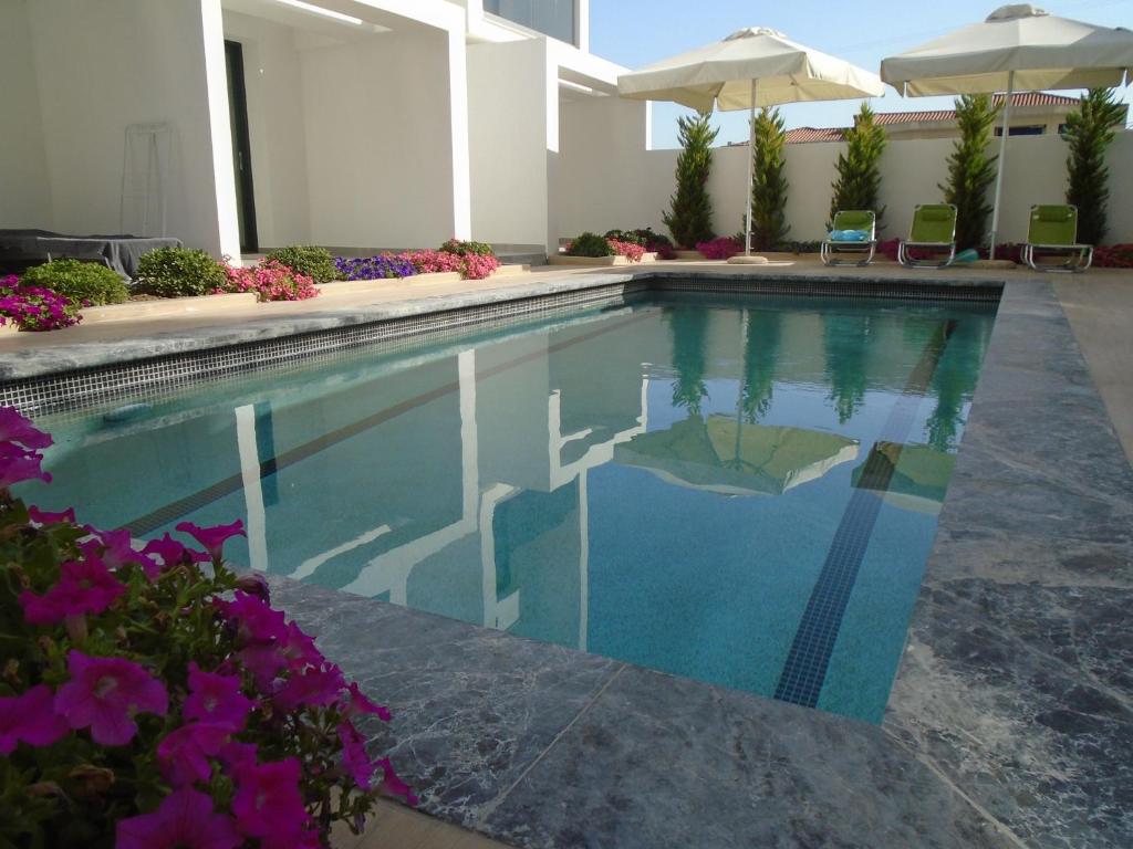 a swimming pool in a hotel with flowers and umbrellas at ASTERIAS Apartment in Kallithea Halkidikis