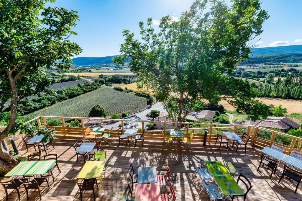 an outdoor patio with tables and chairs and a view of the countryside at Le Nesk Ventoux - Hotel in Sault-de-Vaucluse