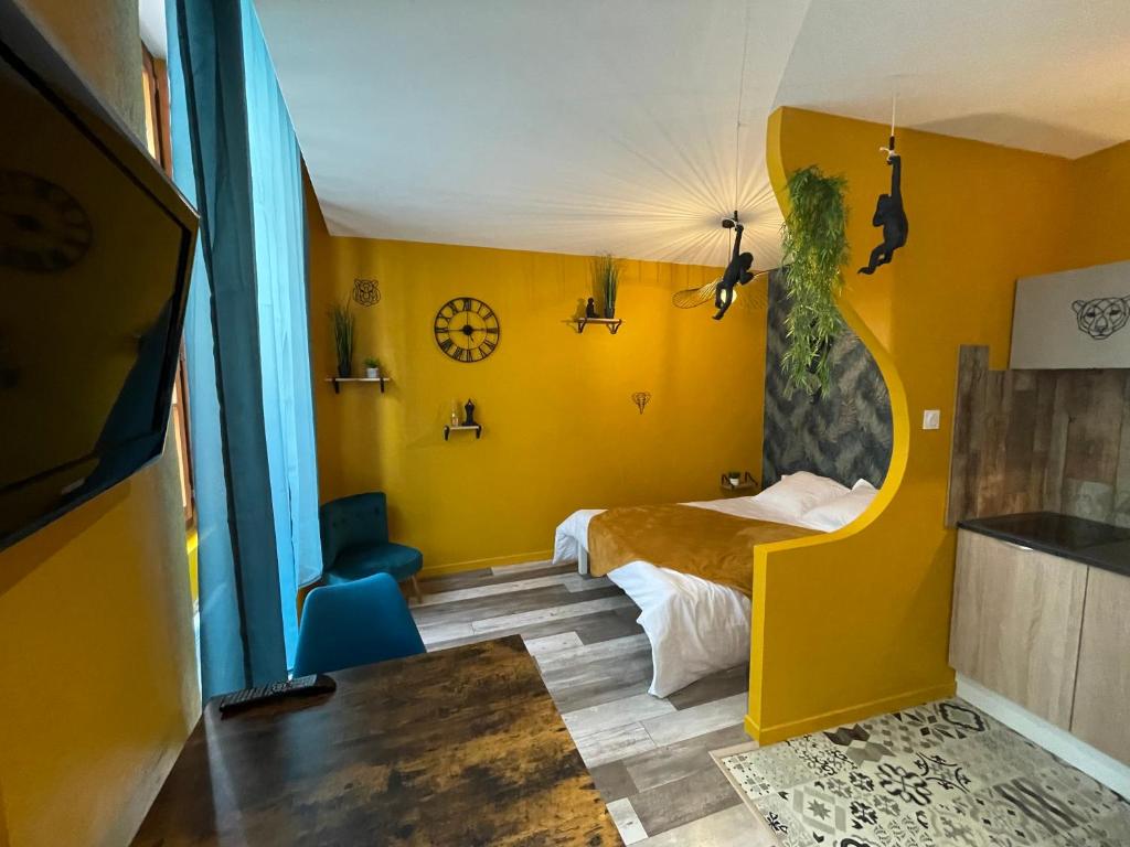 1 dormitorio con paredes amarillas, 1 cama y 1 silla en JuNgLe ROOM, en Romans-sur-Isère
