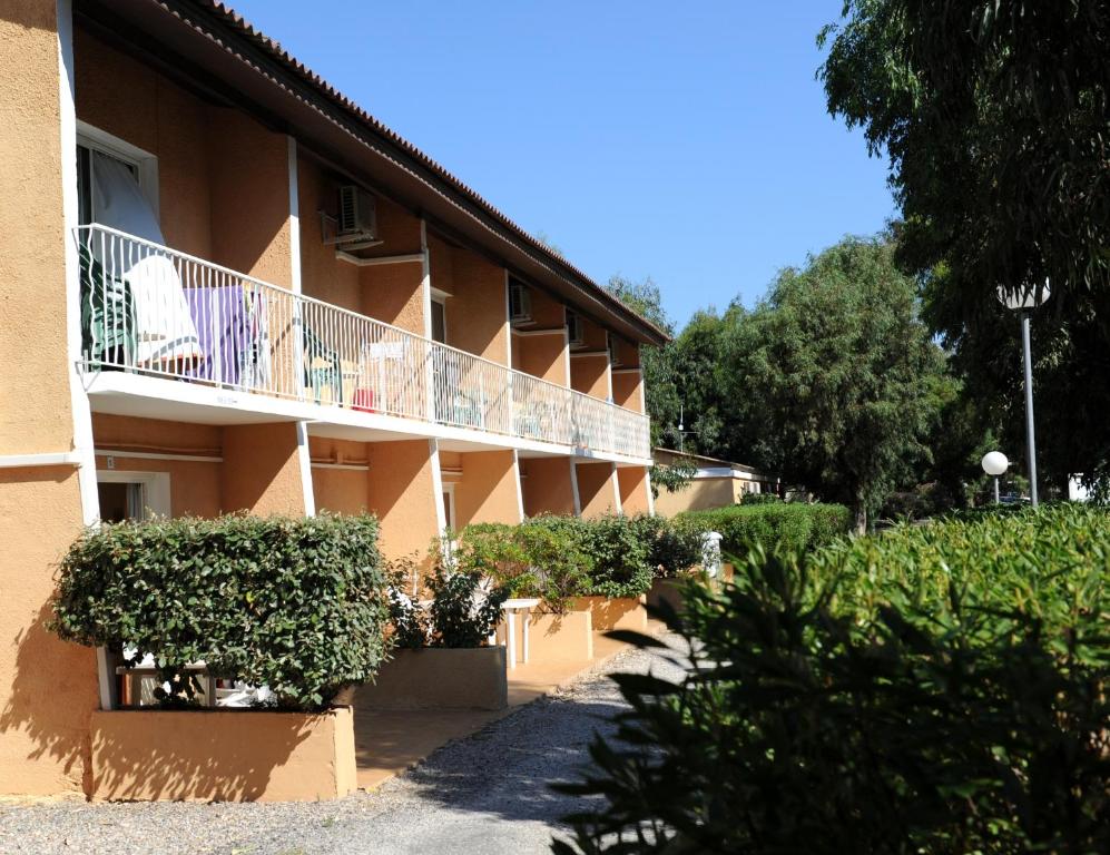 a building with a balcony and bushes in front of it at Résidence Les Castors in Calvi