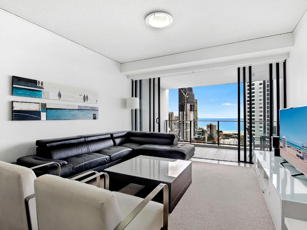a living room with a black leather couch and a tv at Beautiful Ocean View High Floor 3 Bedroom Apartment at Sierra Grand in Gold Coast