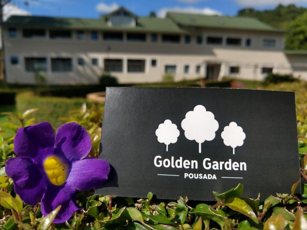 a purple flower sitting next to a garden garden sign at Pousada Golden Garden in Caxambu