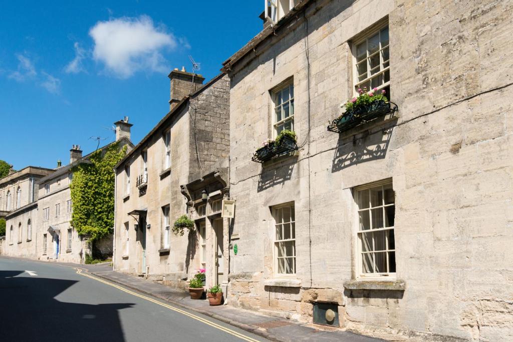 un vieux bâtiment en pierre avec des boîtes de fleurs sur les fenêtres dans l'établissement St Annes Bed and Breakfast, à Painswick