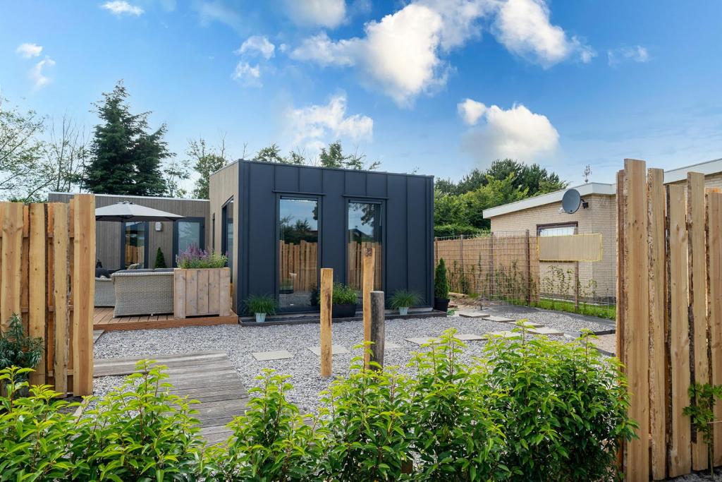 a contemporary house with a black exterior and a wooden fence at Branding 104 - Het Oude Nieuwland Ouddorp NOT INTENDED FOR COMPANY OR WORK-RELATED STAYS in Ouddorp