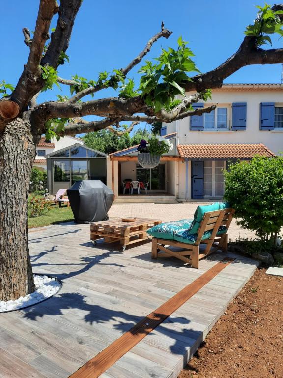 une terrasse avec un banc, une table et un arbre dans l'établissement Gîte ma vie là avec jacuzzi privatif, à Saint-Julien-de-Cassagnas