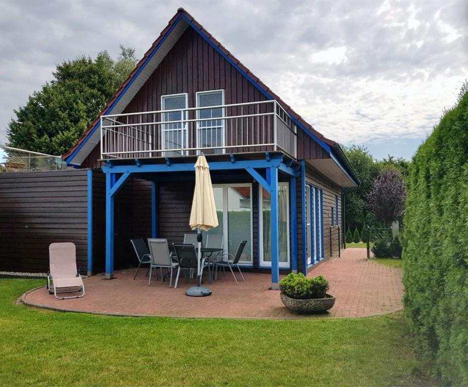 a house with a deck and a patio with chairs and an umbrella at Haus Gestrandet in Kaltenhof