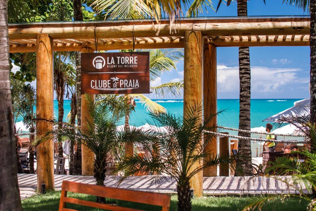 a sign for a hotel with a bench and the ocean at La Torre Resort All Inclusive in Porto Seguro