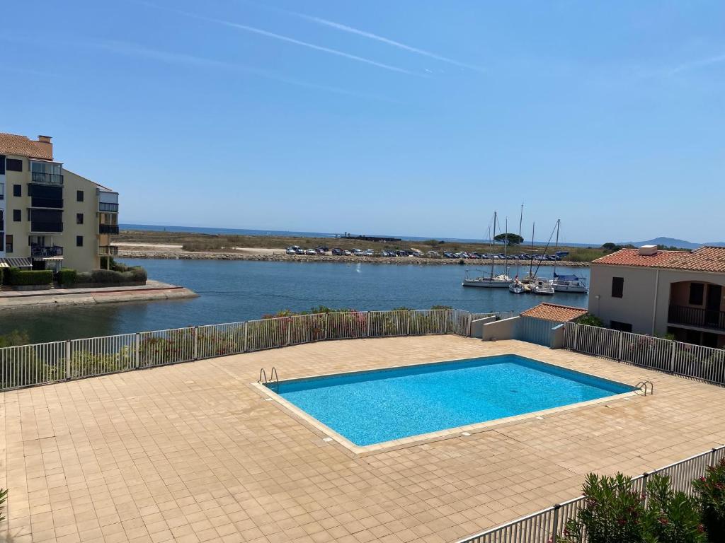 - une piscine sur une terrasse à côté d'une étendue d'eau dans l'établissement Appartement sur la marina vue mer panoramique, à Saint-Cyprien