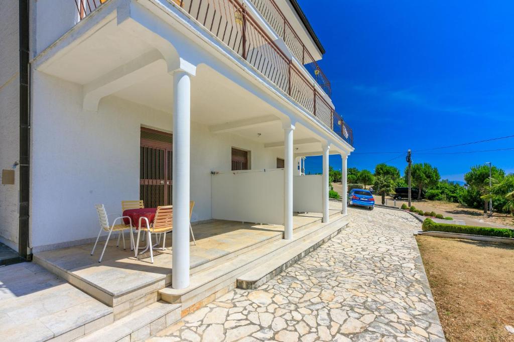 a white house with a porch with a table and chairs at Apartments Laura in Dramalj