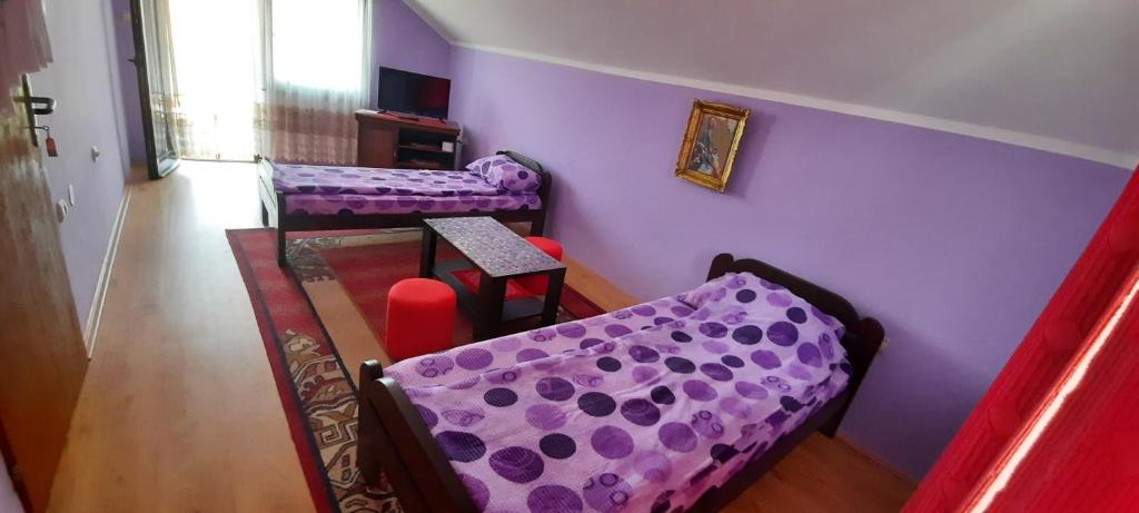 a purple room with two beds and a table at Sobe Seka in Golubac