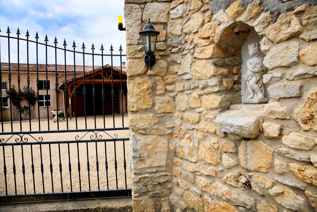 a stone wall with a wrought iron fence and a building at Launie Lea in Eyzerac