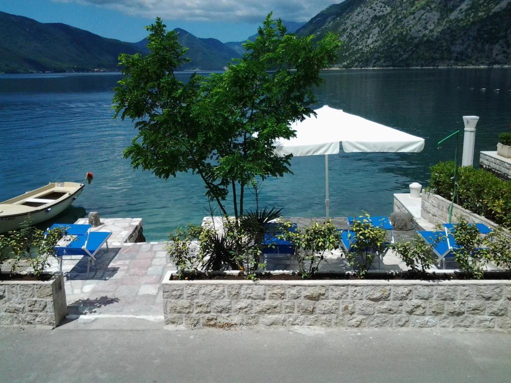 a table and chairs and an umbrella next to a lake at Ljuta Studios in Kotor