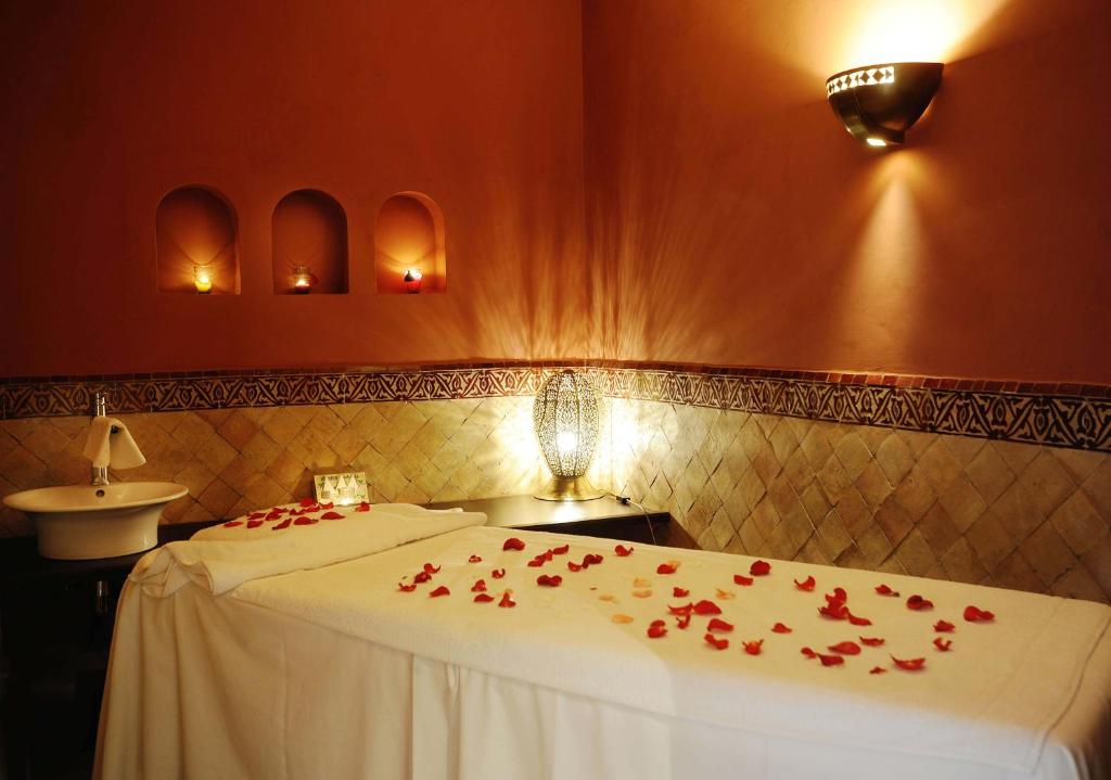 a bedroom with a bed with red rose petals on it at Berbère Palace in Ouarzazate