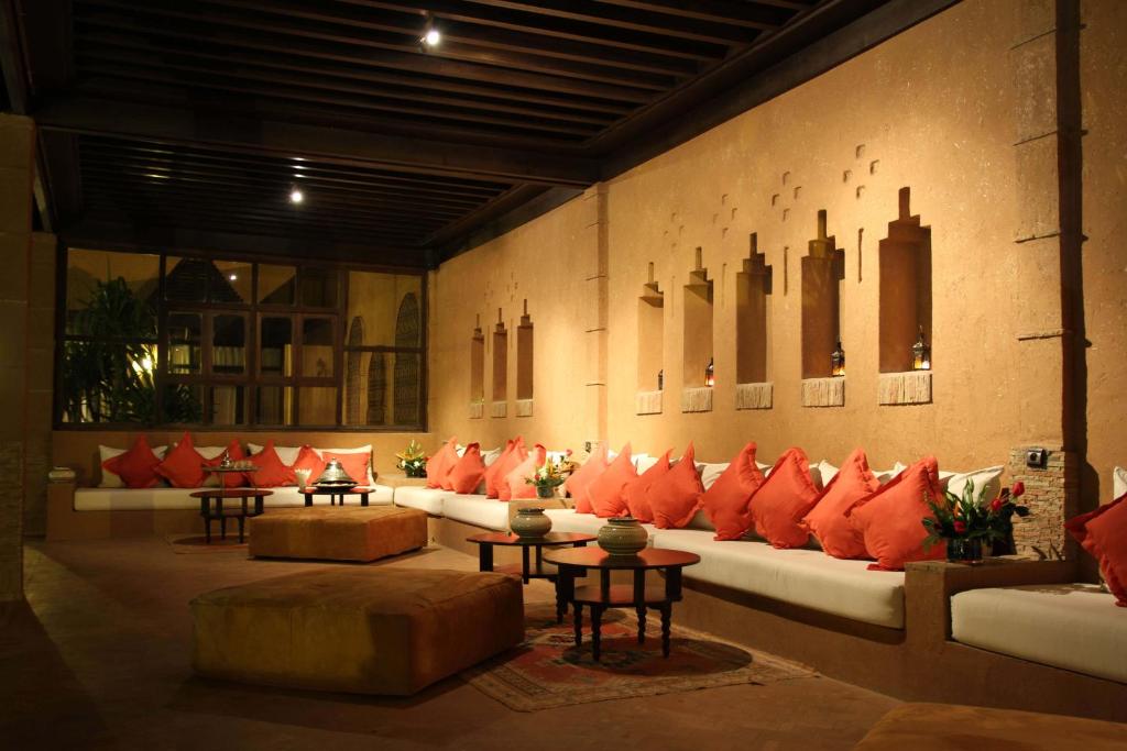 a room with a couch with red pillows and tables at Berbère Palace in Ouarzazate