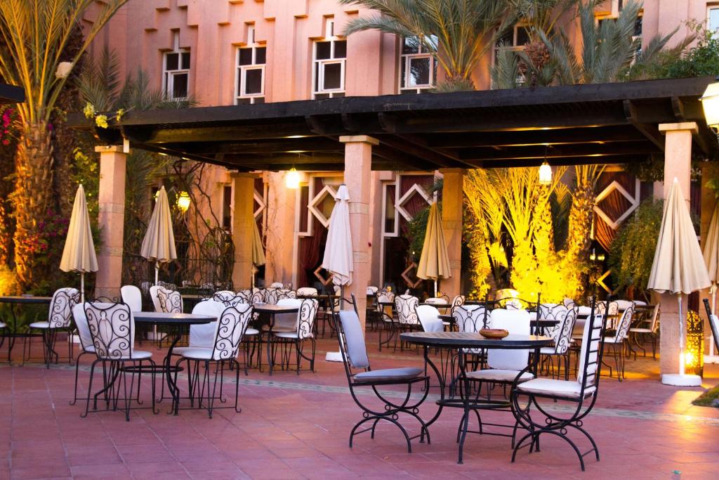 an outdoor patio with tables and chairs and umbrellas at Berbère Palace in Ouarzazate
