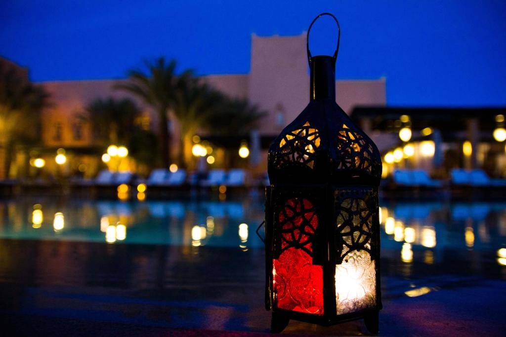 a lantern is sitting next to a pool at night at Berbère Palace in Ouarzazate