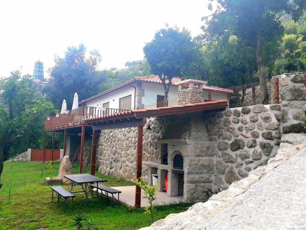 um edifício de pedra com uma mesa e bancos sobre ele em Quinta da Casa Matilde - NATURE HOUSE no Gerês
