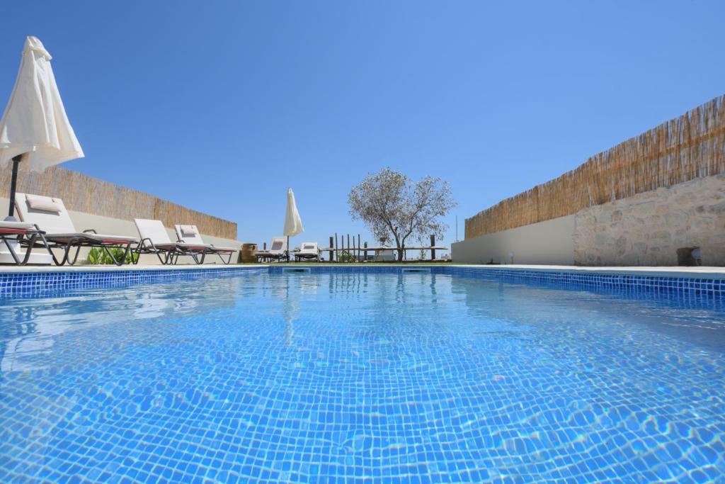 une grande piscine avec des chaises et des parasols dans l'établissement Arismari Villa - Heated Private Pool, à episkopi-heraklion