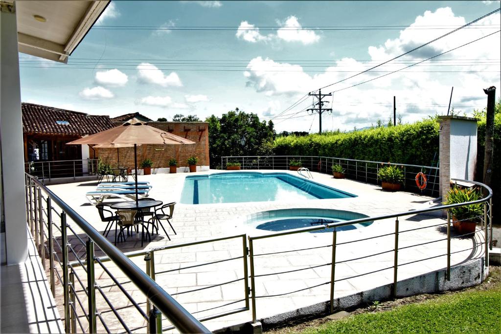 a swimming pool with a table and an umbrella at Amazilia Hotel Campestre ubicado en Cerritos cerca a Ukumari in Pereira