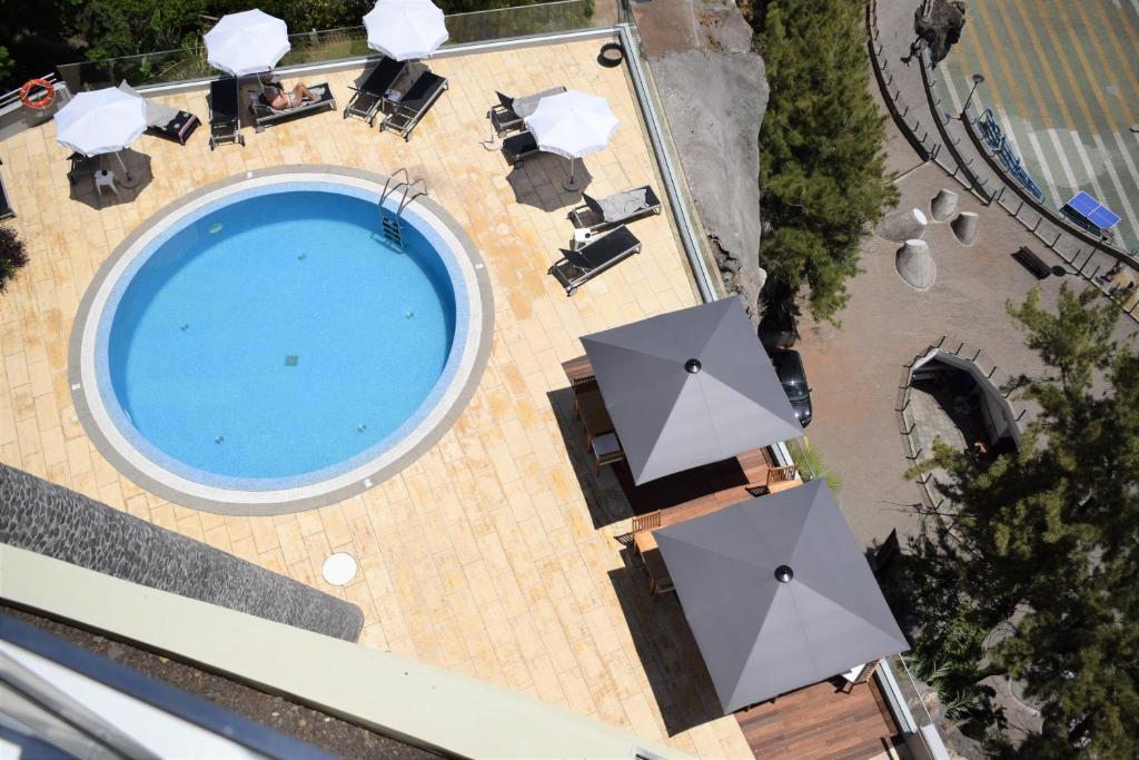 una vista sul tetto di una piscina con ombrelloni di Madeira Regency Cliff - Adults Only a Funchal