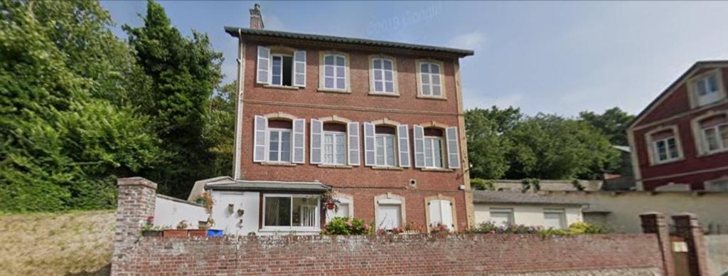 ein altes Backsteinhaus mit Ziegelwand in der Unterkunft Appartements a 5 minutes de la mer a pied in Étretat