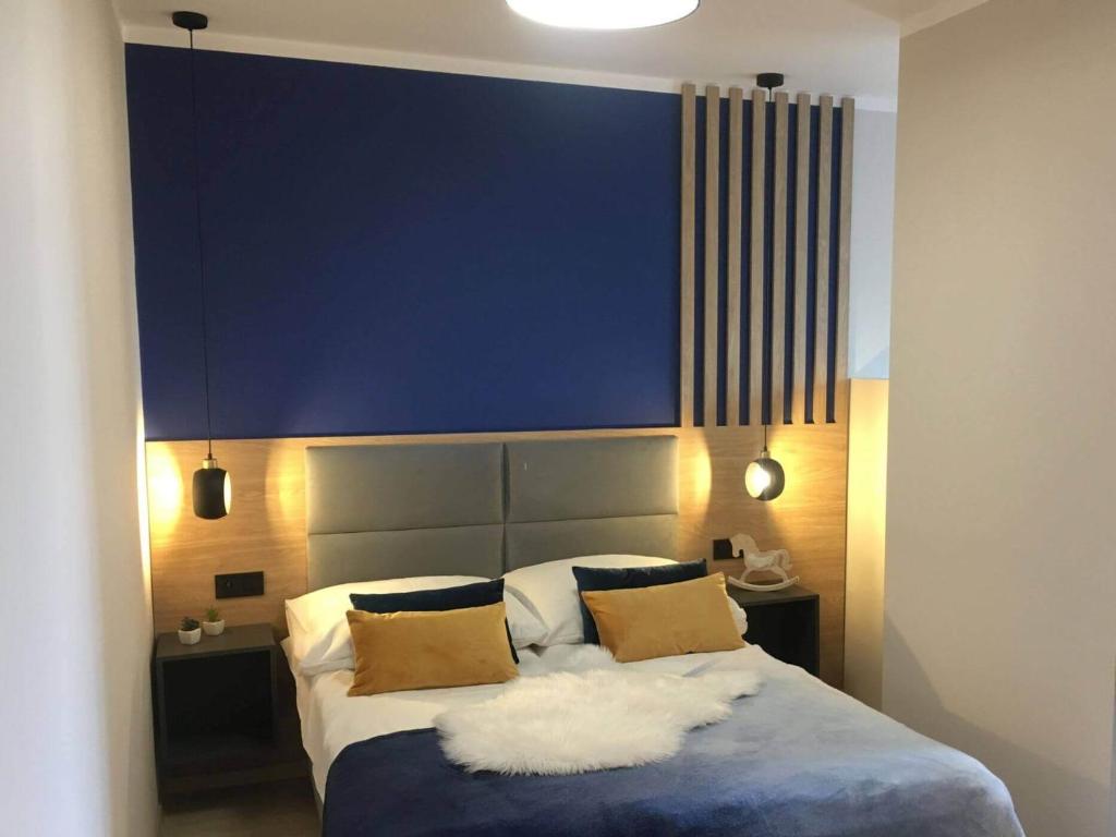 a bedroom with a large bed with a blue wall at Koralia Domki i Apartamenty Basen z podgrzewaną wodą in Sarbinowo