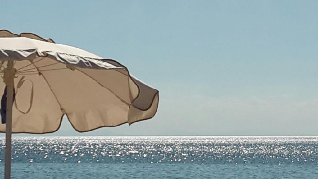 an umbrella sitting on the beach next to the ocean at appartamento VENTO in Pulsano