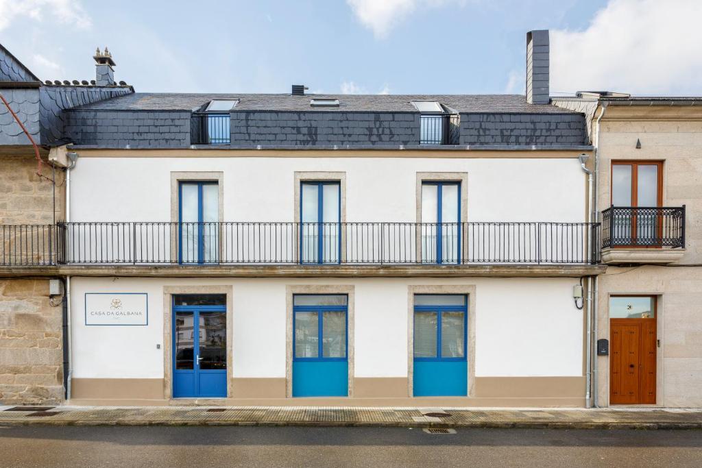 ein Apartmenthaus mit blauen Türen und einem Balkon in der Unterkunft Hotel Casa da Galbana in Friol