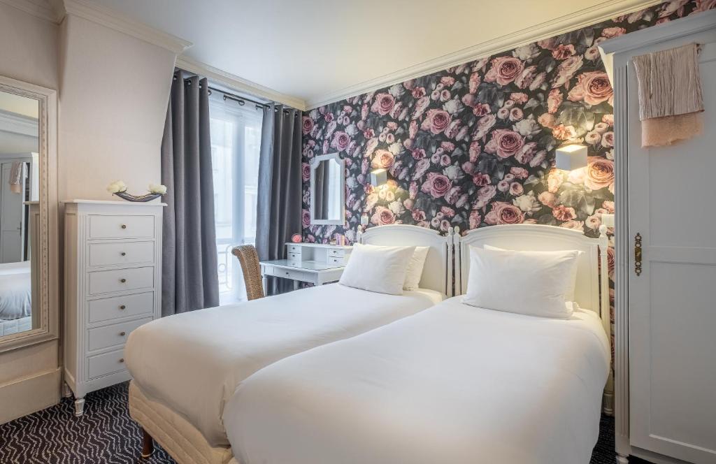 two beds in a room with a floral wallpaper at Hotel London in Paris