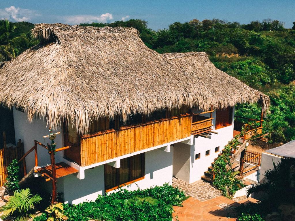 a large building with a thatched roof with trees at Hotel el Risco in Cuatunalco