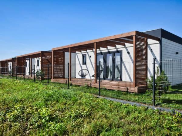 una casa con una valla en un campo en New Wave Resort Mielno en Mielno