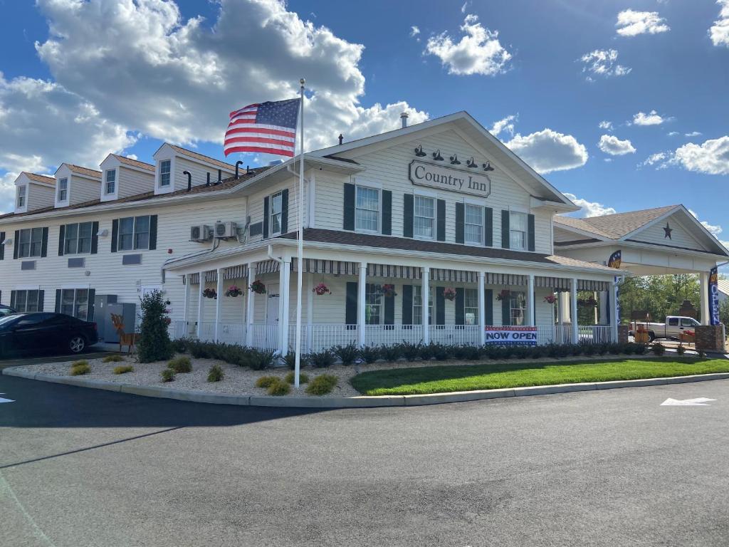 un gran edificio blanco con una bandera americana en él en Country Inn of Hazlet en Hazlet