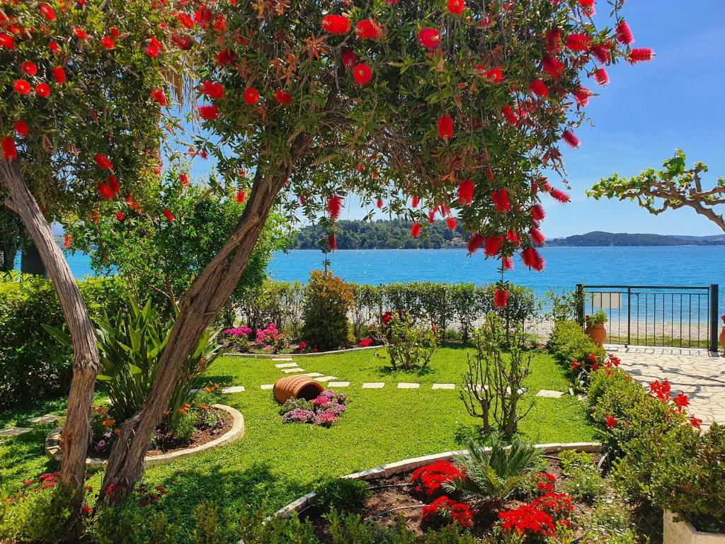 un giardino fiorito e un albero con fiori rossi di Daglas Beach House a Nydri
