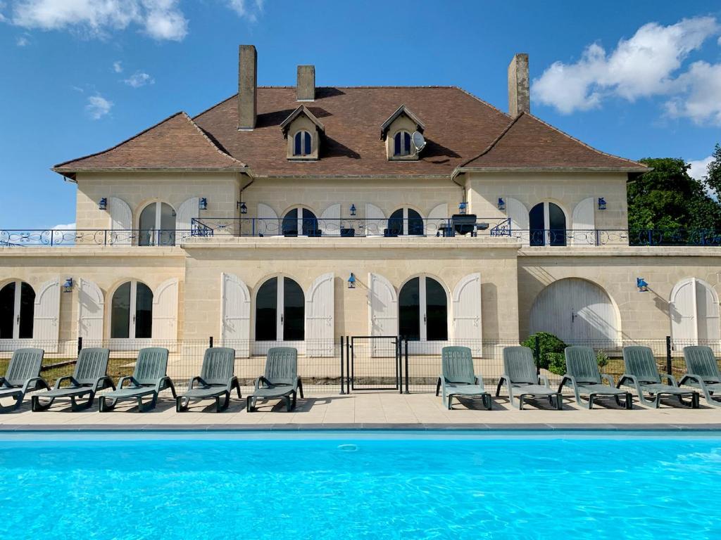 un grupo de sillas sentadas frente a un edificio en Magnifique villa de charme avec piscine, en Casteljaloux