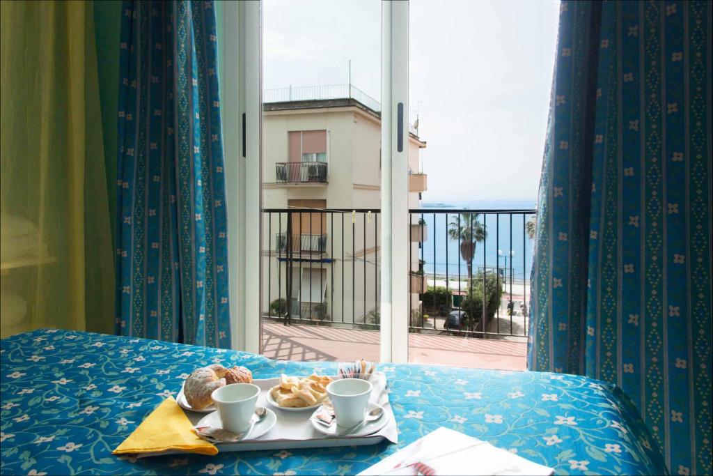 taca z ciastkami i kubkami na stole z oknem w obiekcie Hotel Elisabetta w mieście Sestri Levante