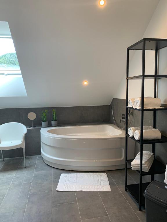 a bathroom with a white tub and a white chair at FreiRaum in Annweiler am Trifels