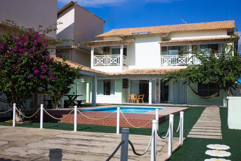 a villa with a swimming pool in front of a house at Casa das Dunas in Cabo Frio