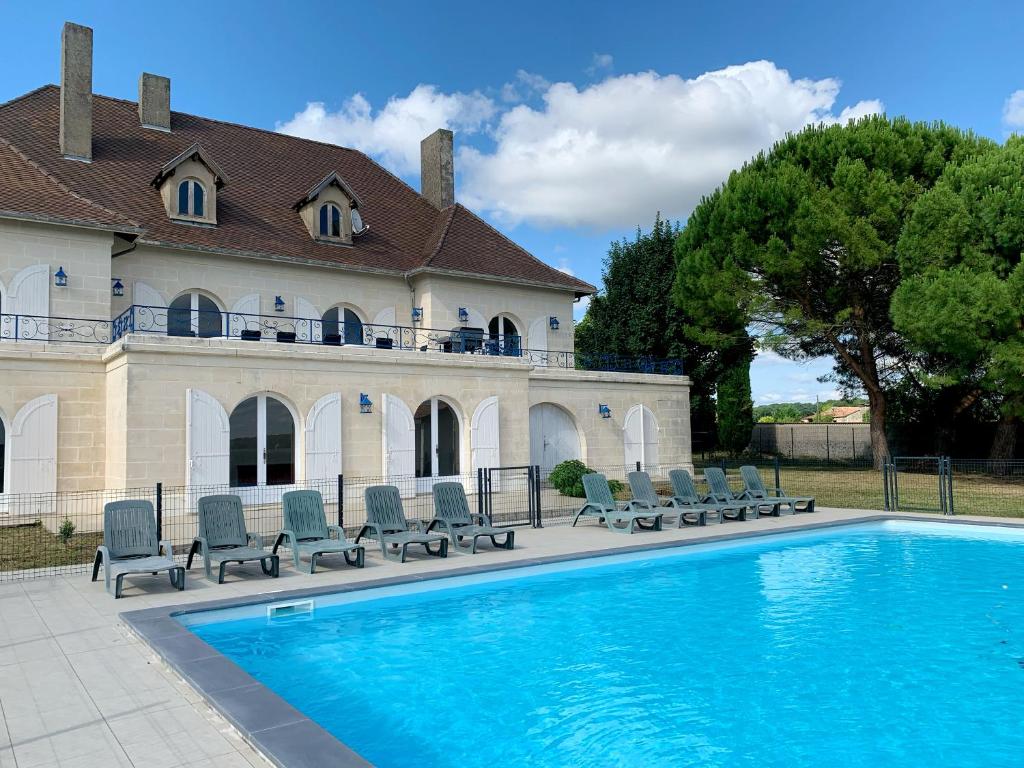 a swimming pool in front of a building with chairs at Magnifique villa de charme avec piscine in Casteljaloux