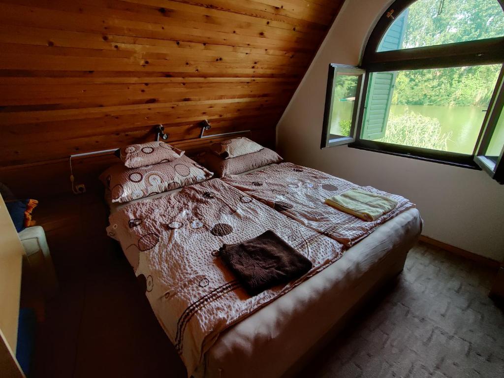 a bedroom with a bed in a cabin with a window at Tobak vendégház in Békésszentandrás