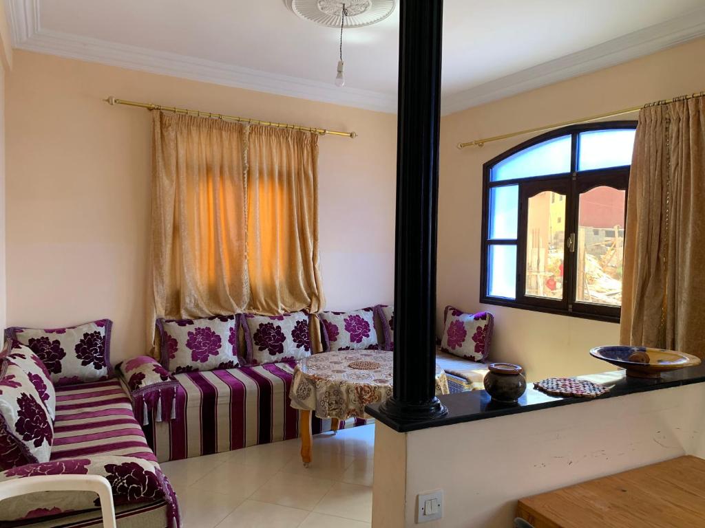 een woonkamer met paarse meubels en een raam bij Dar Amallay in Tamraght Ou Fella